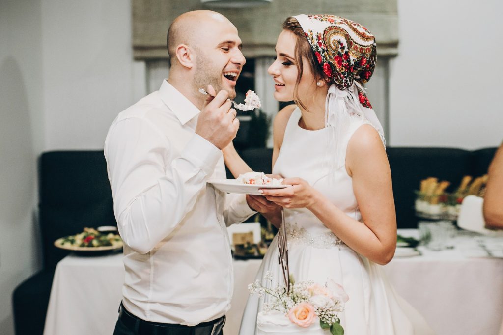 Bride and groom tasting stylish wedding cake at wedding reception
